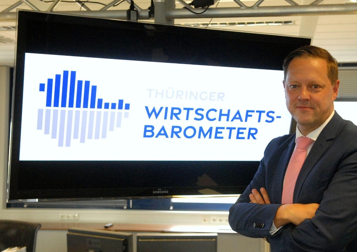 Geschäftsführer Michael Tallai vor dem Logo des Thüringer Wirtschaftsbarometers